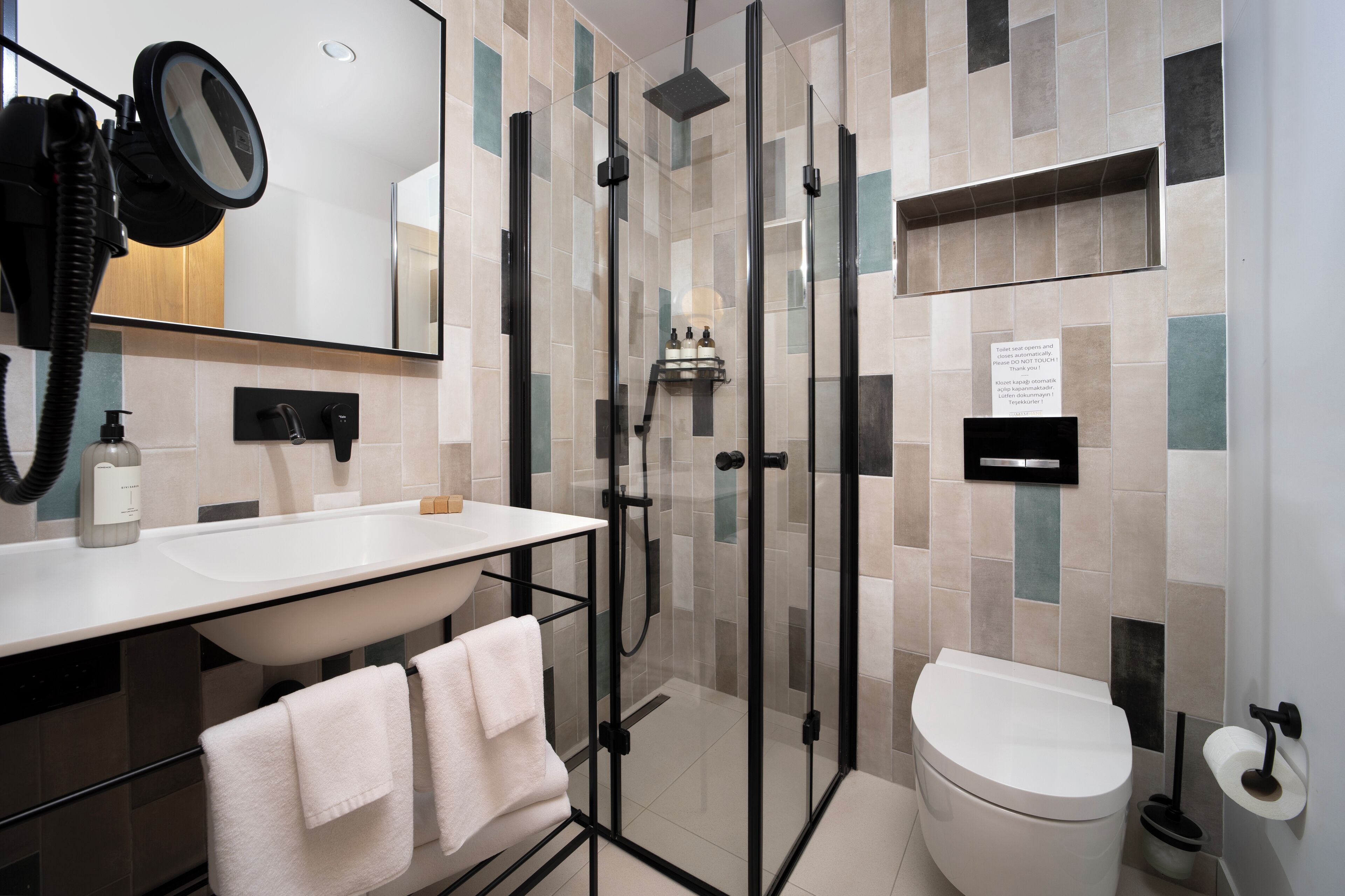 Un baño moderno con ducha envuelta en vidrio, un lavabo blanco y un inodoro.