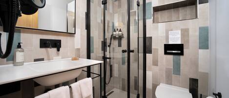 Un baño moderno con ducha envuelta en vidrio, un lavabo blanco y un inodoro.
