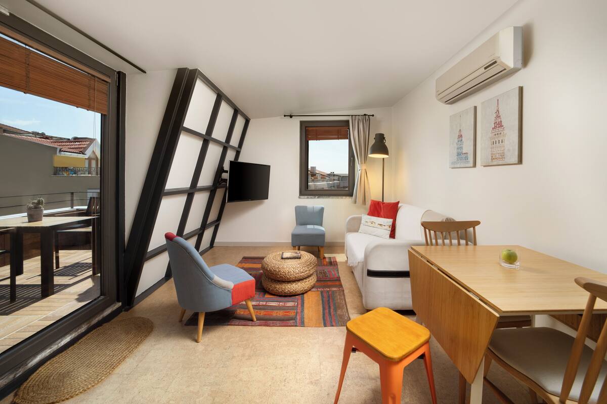 Un salon moderne comprenant un canapé, des fauteuils, une table à manger et un téléviseur.