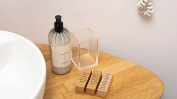A bathroom with a white sink, a glass bottle, a clear cube, and three brown boxes with text.