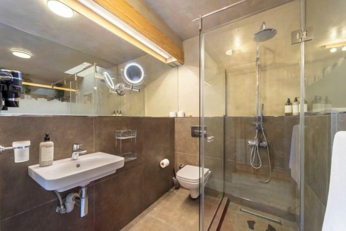 A modern bathroom with a glass-enclosed shower, a sink with a mirror, and a toilet.