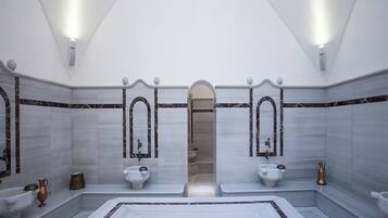 Bathroom features two sinks, decorative columns, and a geometric patterned floor.