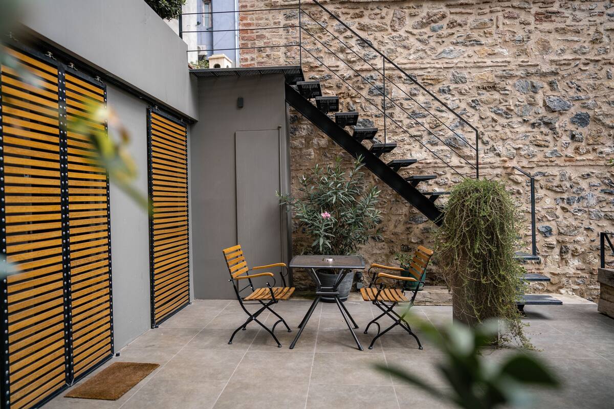 Une terrasse avec une table et des chaises, un escalier et un mur en pierre.