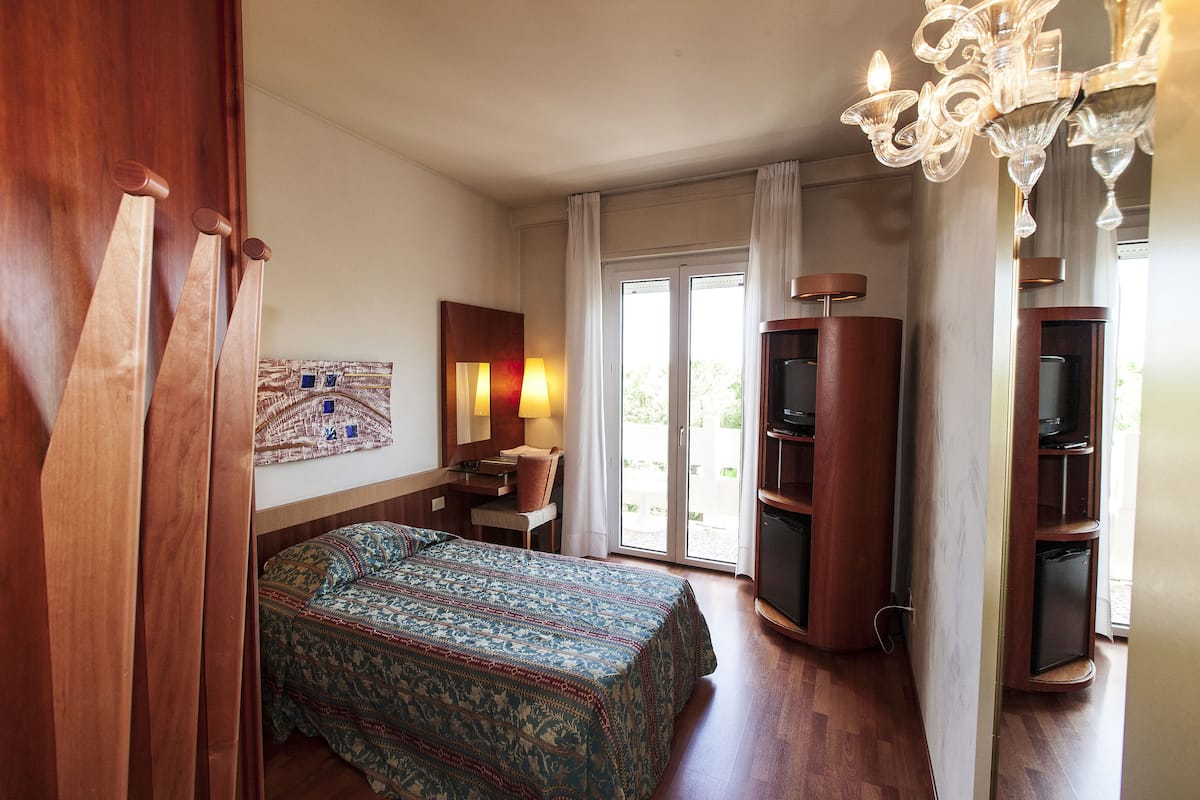 Une chambre d’hôtel équipée d’un lit, d’un bureau, d’une chaise, d’une télévision et d’un lustre.