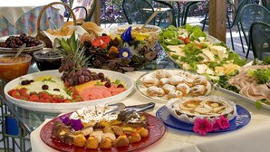 Ein reichhaltiges Buffet im Freien mit verschiedenen Speisen und Blick auf einen Garten.