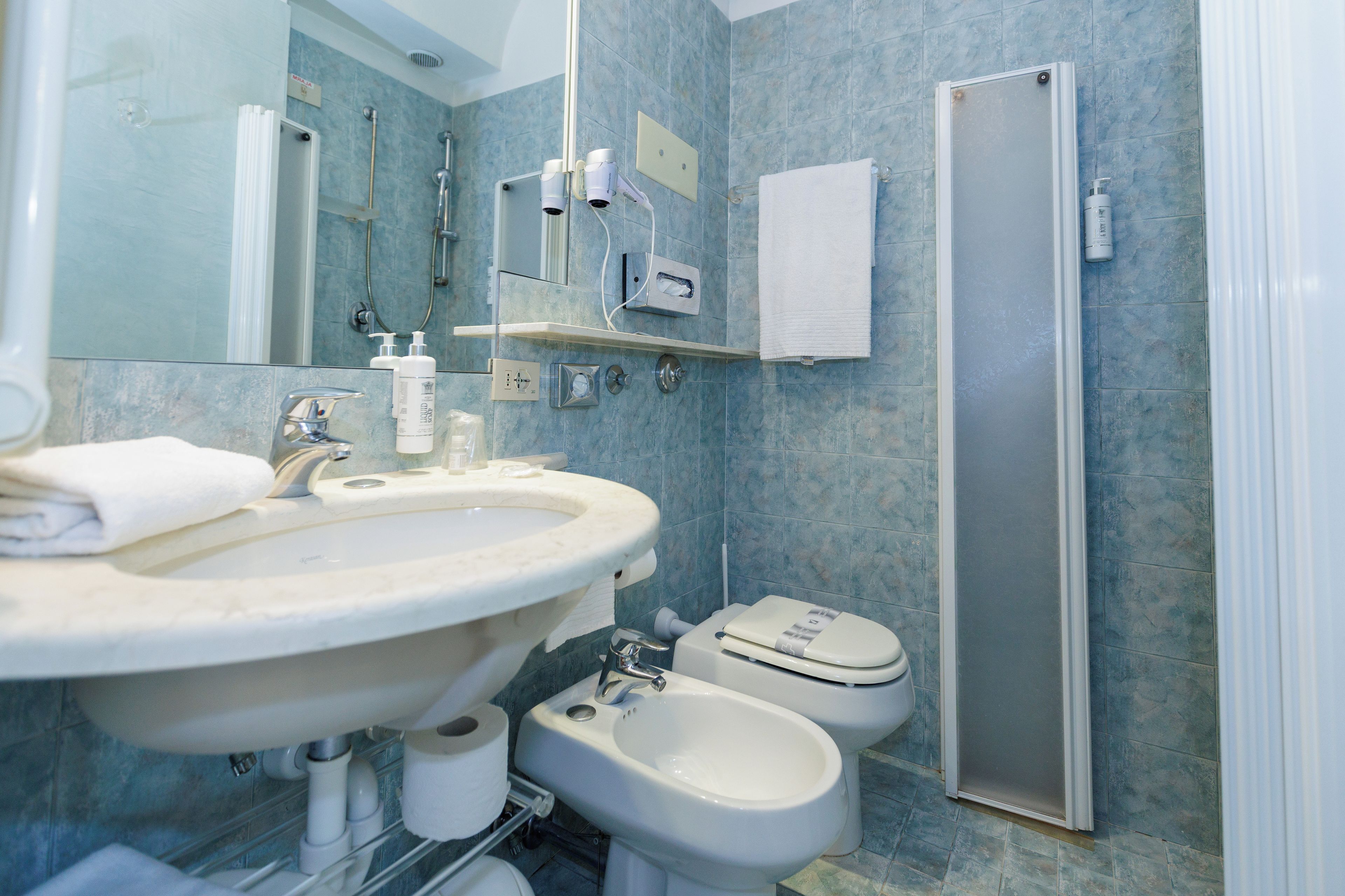 Un bagno con lavandino, specchio, asciugamano, WC, bidet e cabina doccia.