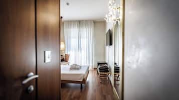 A hotel room with a bed, a bedside table, a lamp, a mirror, and a chandelier.