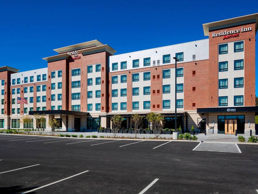 A multi-story hotel with a brick facade, large windows, and a parking lot in front.