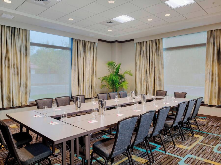 A conference room with a long table, chairs, and a projector screen.