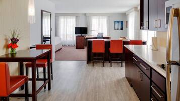 Una habitación de hotel moderna con comedor, televisión y cocina.