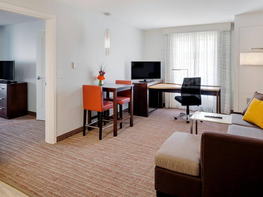Habitación de hotel con comedor, televisor, sofá y lámpara.
