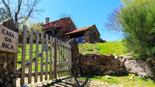 Ein rustikales Steinhaus mit einem Holztor und einem Schild mit der Aufschrift 'CASA DA BICA'.
