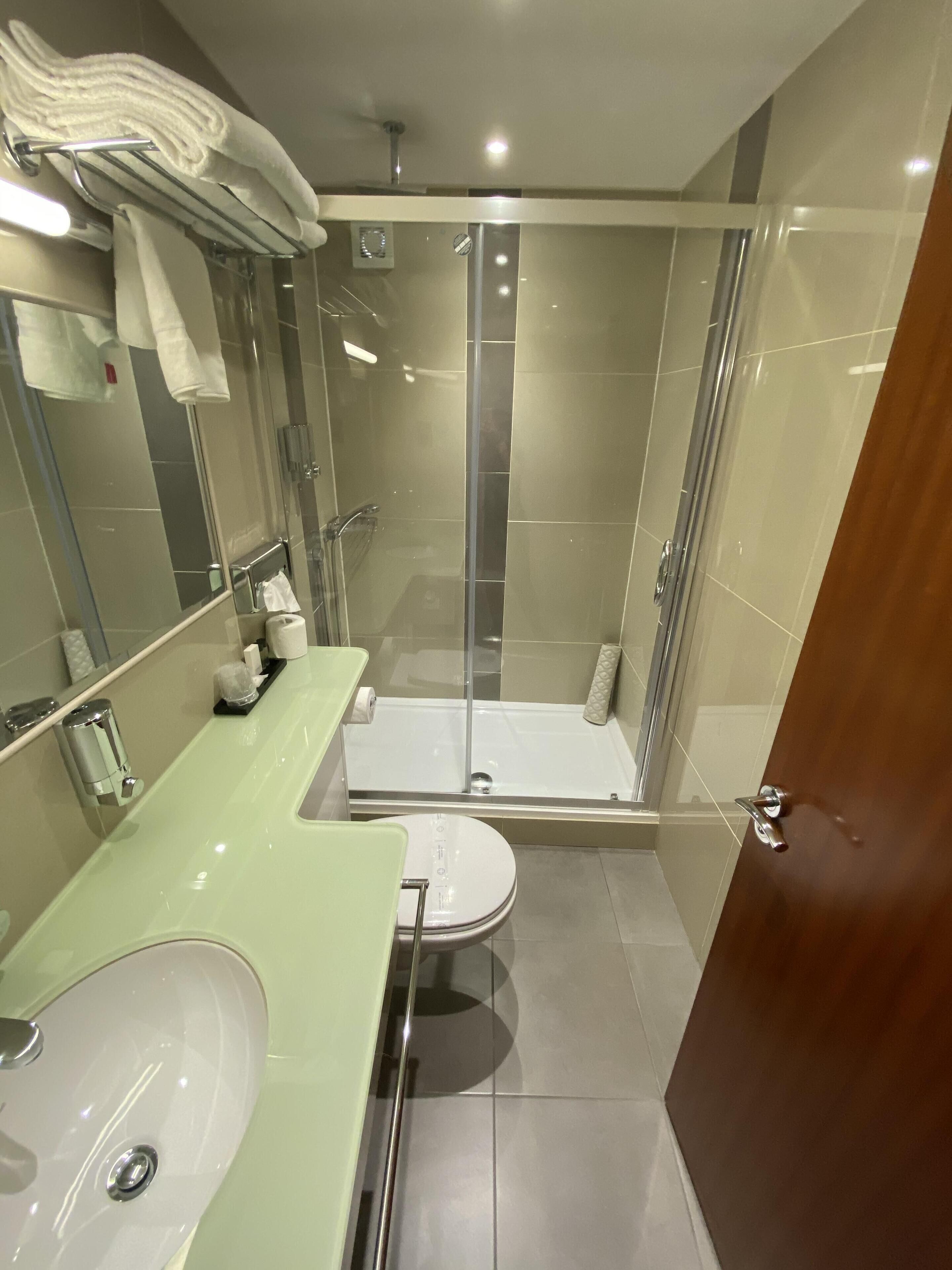 A modern bathroom with a glass-enclosed shower, a sink, and a toilet.