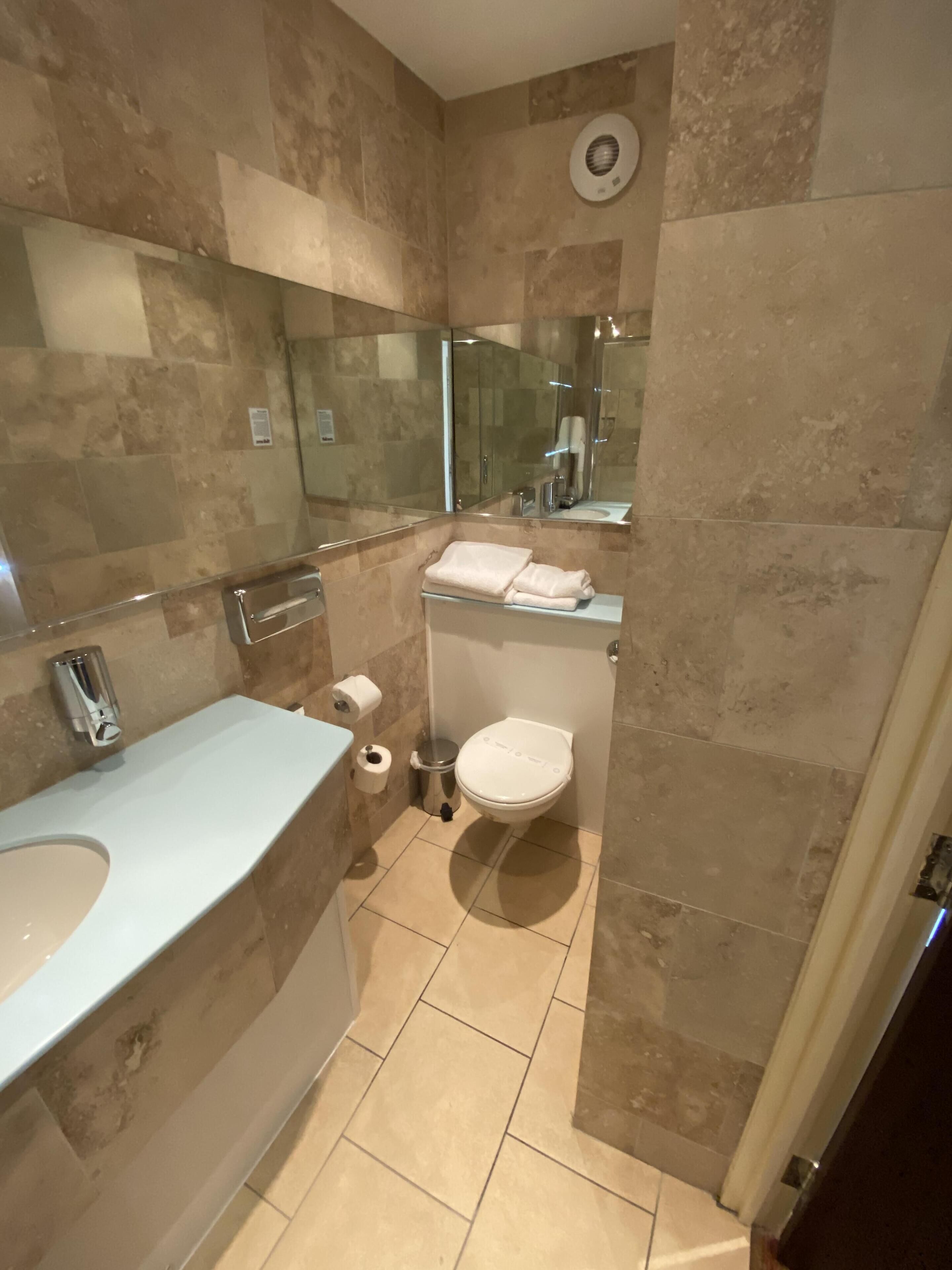 A bathroom with a sink, toilet, and a mirror.