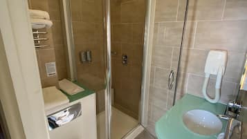 Et moderne badeværelse med et brusebad med glasvægge, et hvidt toilet, en grøn vask og et håndholdt brusehoved.