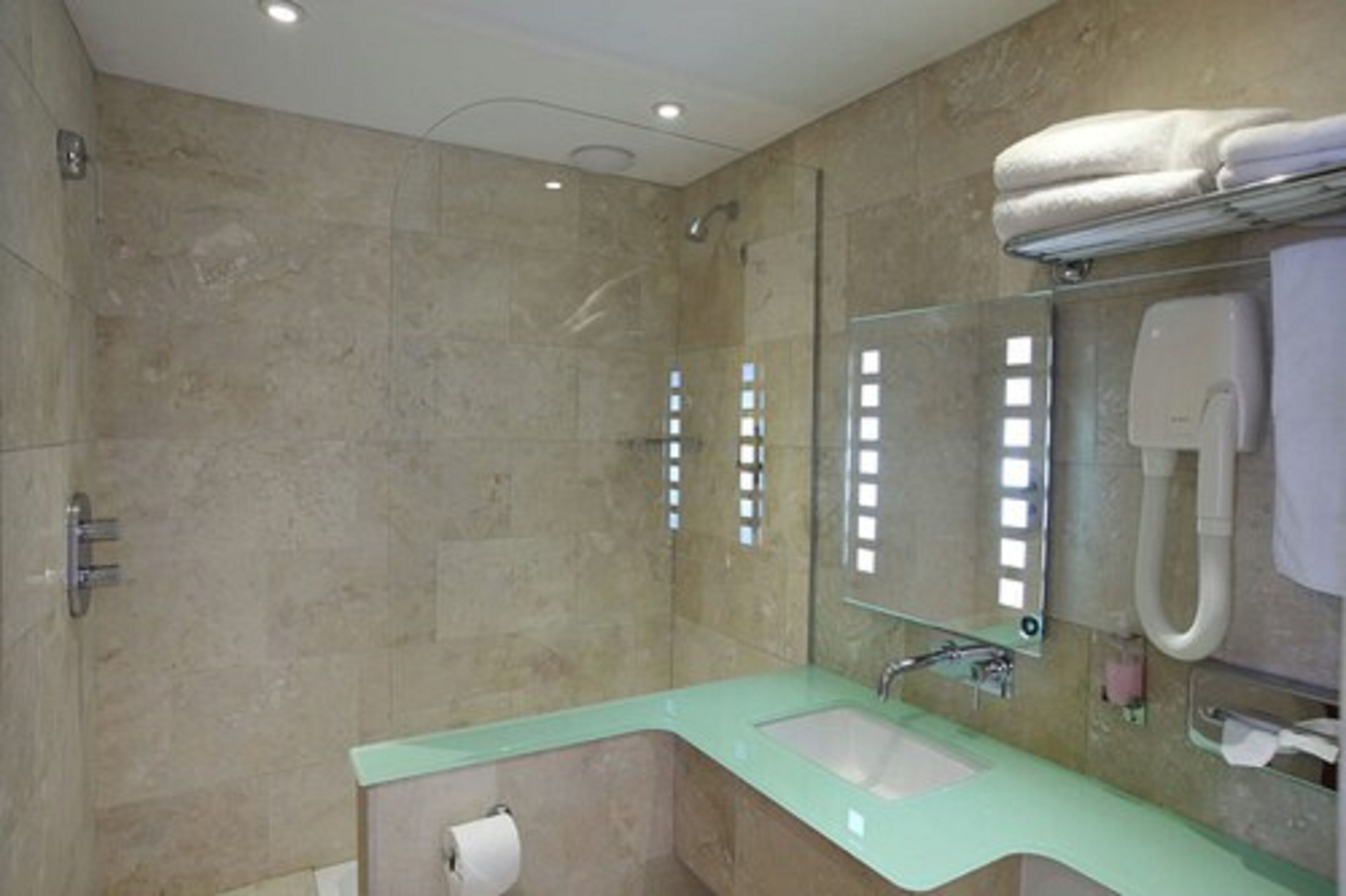 A bathroom with a shower, a sink, a mirror, and a towel rack.