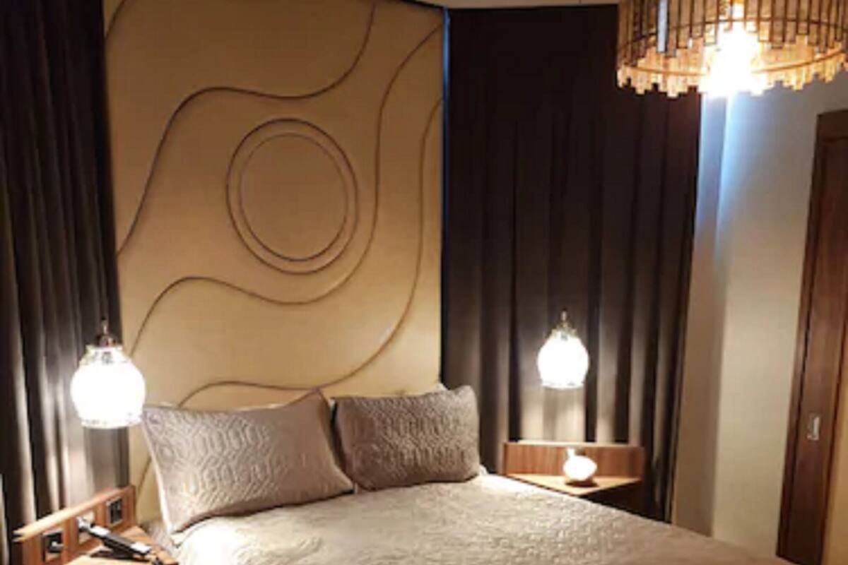 A neatly made bed with a textured blanket, two bedside lamps, and a modern headboard with a circular design.
