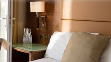 Een hotelkamer met een houten hoofdeinde, een nachtkastje met een lamp en een glas water.
