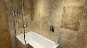 A modern bathroom with a glass-enclosed shower, a freestanding bathtub, and a toilet.