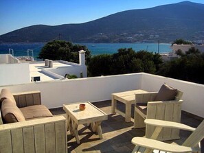 A rooftop terrace with outdoor furniture, a view of the sea, and a mountain in the background. - Aerina Luxury Apartments (Sifnos)