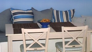 A room with a bed, a table with chairs, and a bowl of fruit on the table.