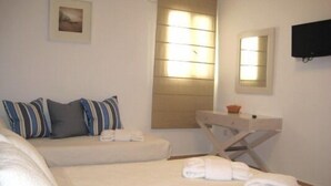 A hotel room with a bed, a bedside table, a mirror, and a window with blinds.