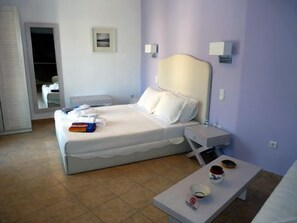 Un dormitorio ordenado con una cama, mesitas de noche y una pequeña mesa con un cuenco y un tarro.