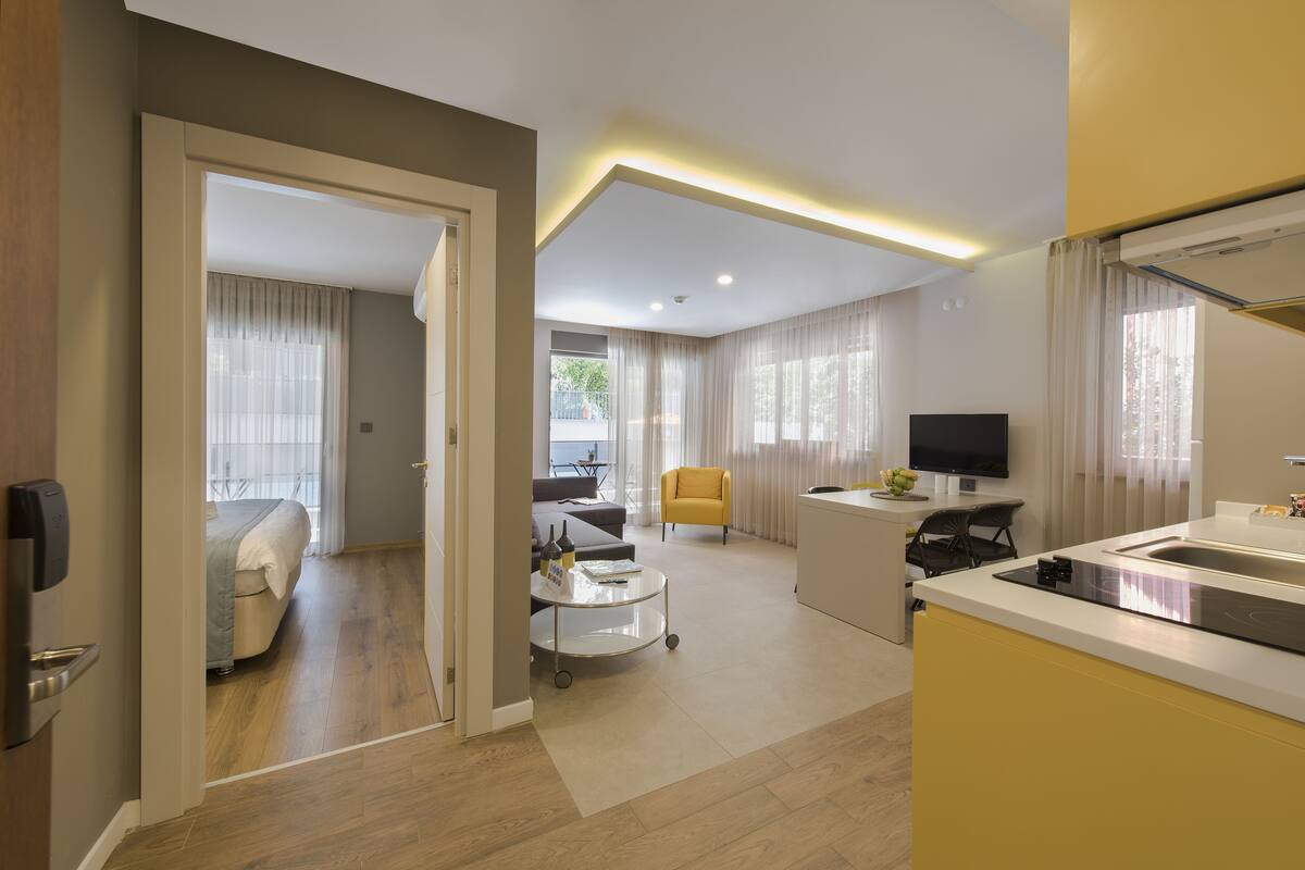 Une chambre d’hôtel moderne équipée d’un lit, d’un bureau, d’une chaise, d’une télévision et d’un coin cuisine.