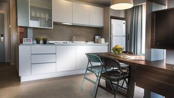 A modern kitchen with white cabinetry, a built-in oven, and a dining area with a wooden table and two chairs.
