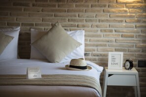 A neatly made bed with a striped bedspread, a beige hat, and a framed sign on a bedside table. - Trend Suites (Konyaalti)