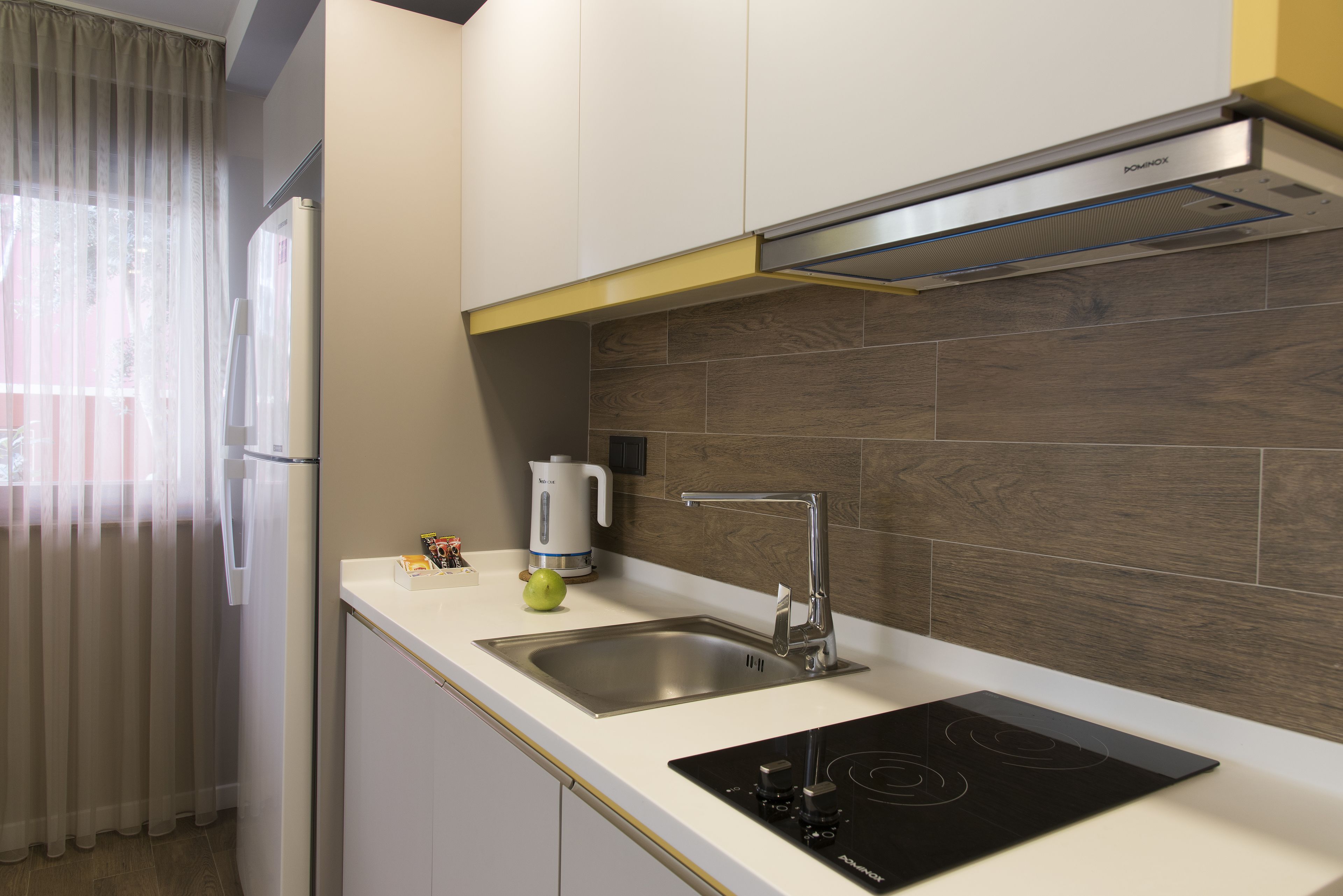 A modern kitchen with a built-in sink, a stainless steel range hood, and a black induction cooktop.