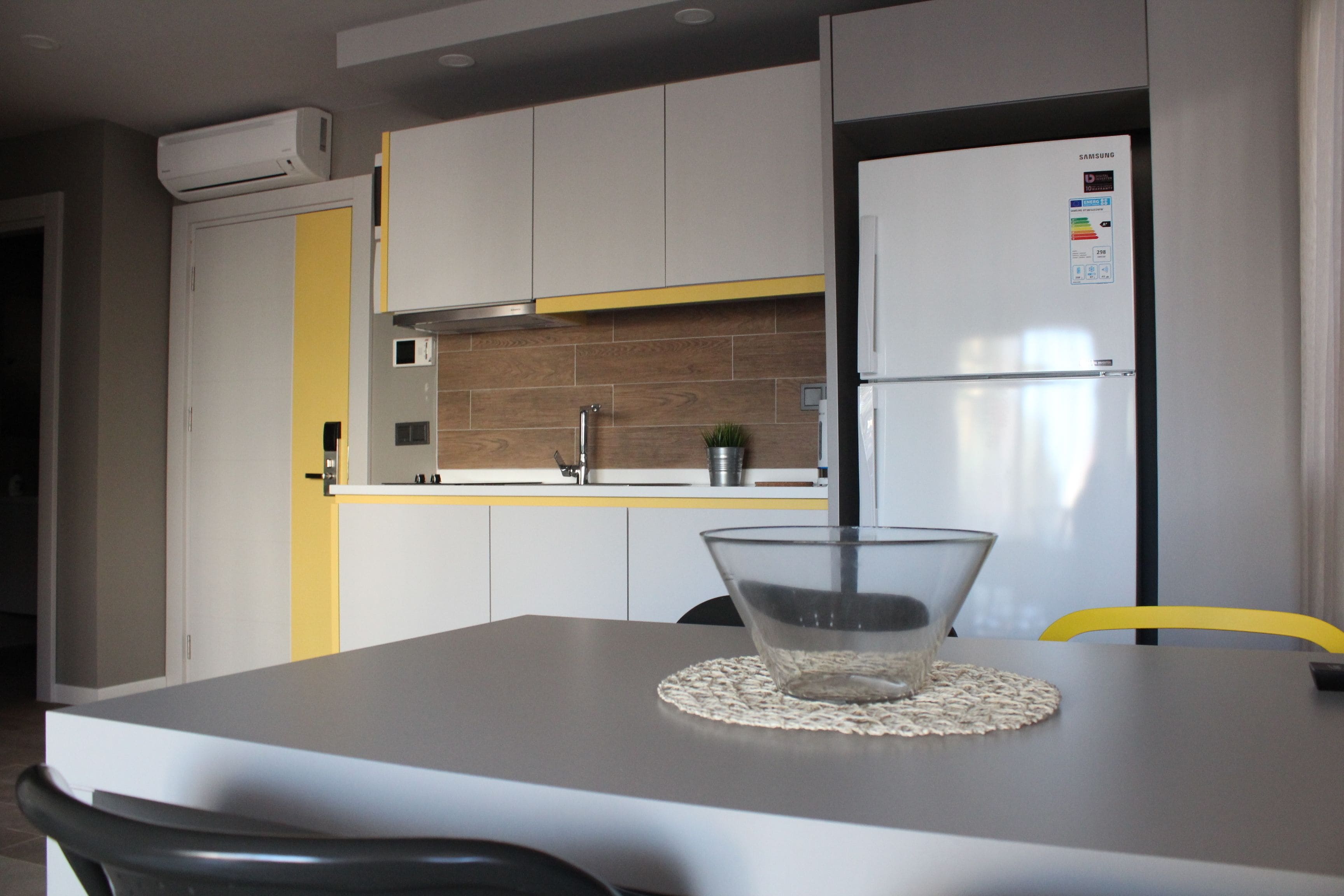 A modern kitchen with white cabinets, a built-in oven, and a Samsung refrigerator.