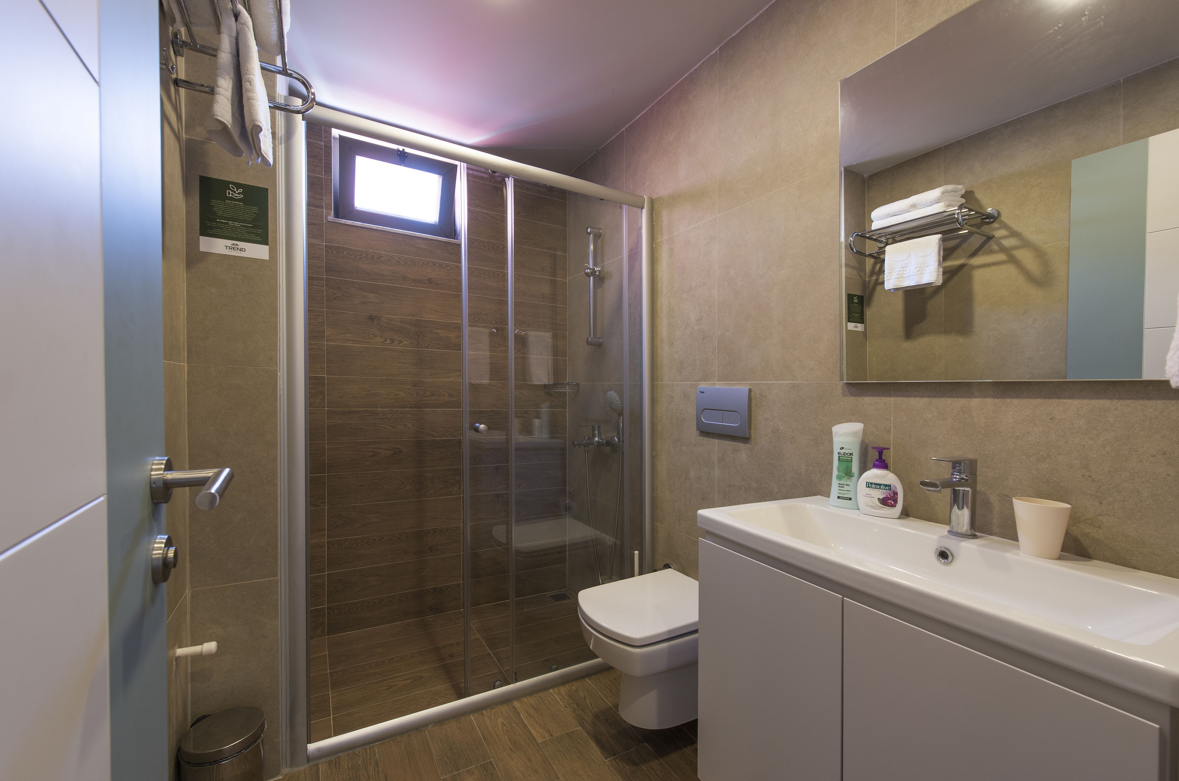 A modern bathroom with a glass-enclosed shower, a toilet, and a sink with toiletries.