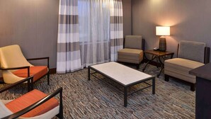 Ein Hotelzimmer mit Teppichboden, einer Couch, zwei Sesseln, einem kleinen Tisch und einer Lampe.