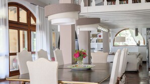Un comedor con una mesa grande, sillas y un jarrón de flores.