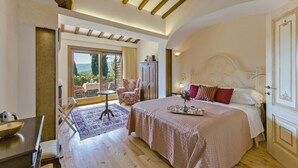 Un dormitorio con una cama grande, una silla, una mesa y vistas al exterior.