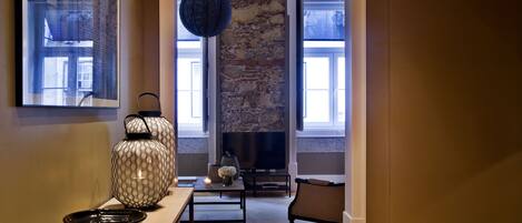 A living room with a stone wall, a fireplace, a television, and a sofa.