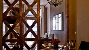 A dining area with a wooden partition, a table set with wine glasses, a candle, and a vase with flowers. - Lisbon Five Stars Apartments São Paulo 55 (Lisbon)