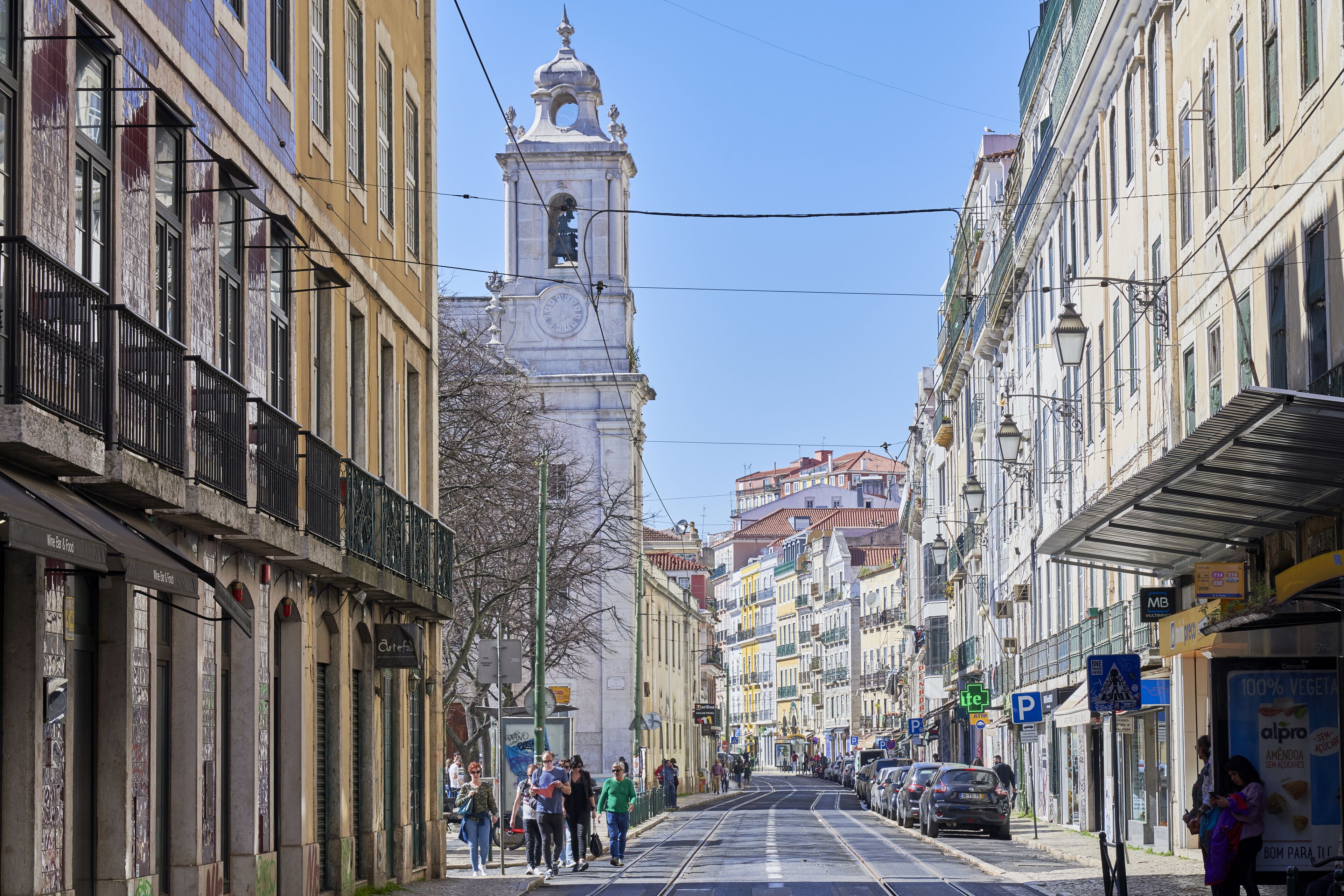 Una strada con edifici, una torre dell'orologio e passanti.