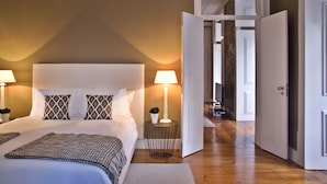 A bedroom with a large bed, two bedside lamps, and a bedside table with a lamp and a plant. - Lisbon Five Stars Apartments São Paulo 55 (Lisbon)
