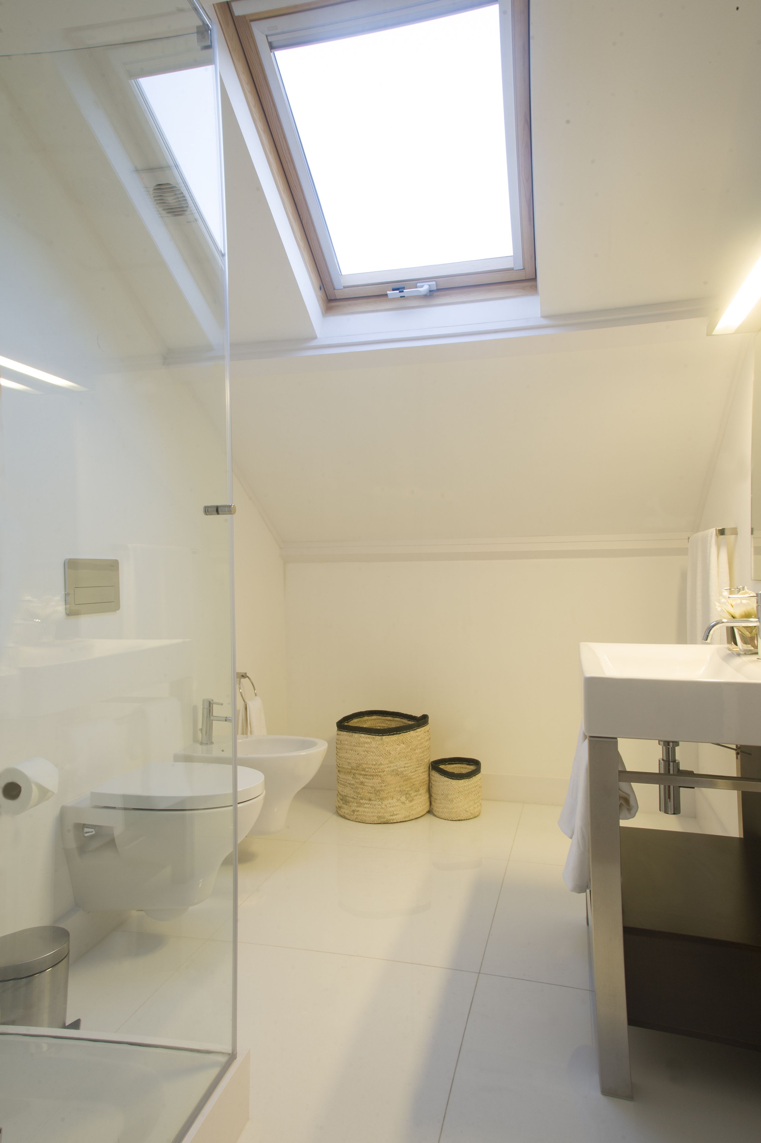 Une salle de bain moderne avec un puits de lumière, un lavabo blanc et des toilettes.