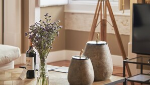 A room with a wooden coffee table, a vase with flowers, a bottle, and two textured vases. - Lisbon Five Stars Apartments São Paulo 55 (Lisbon)