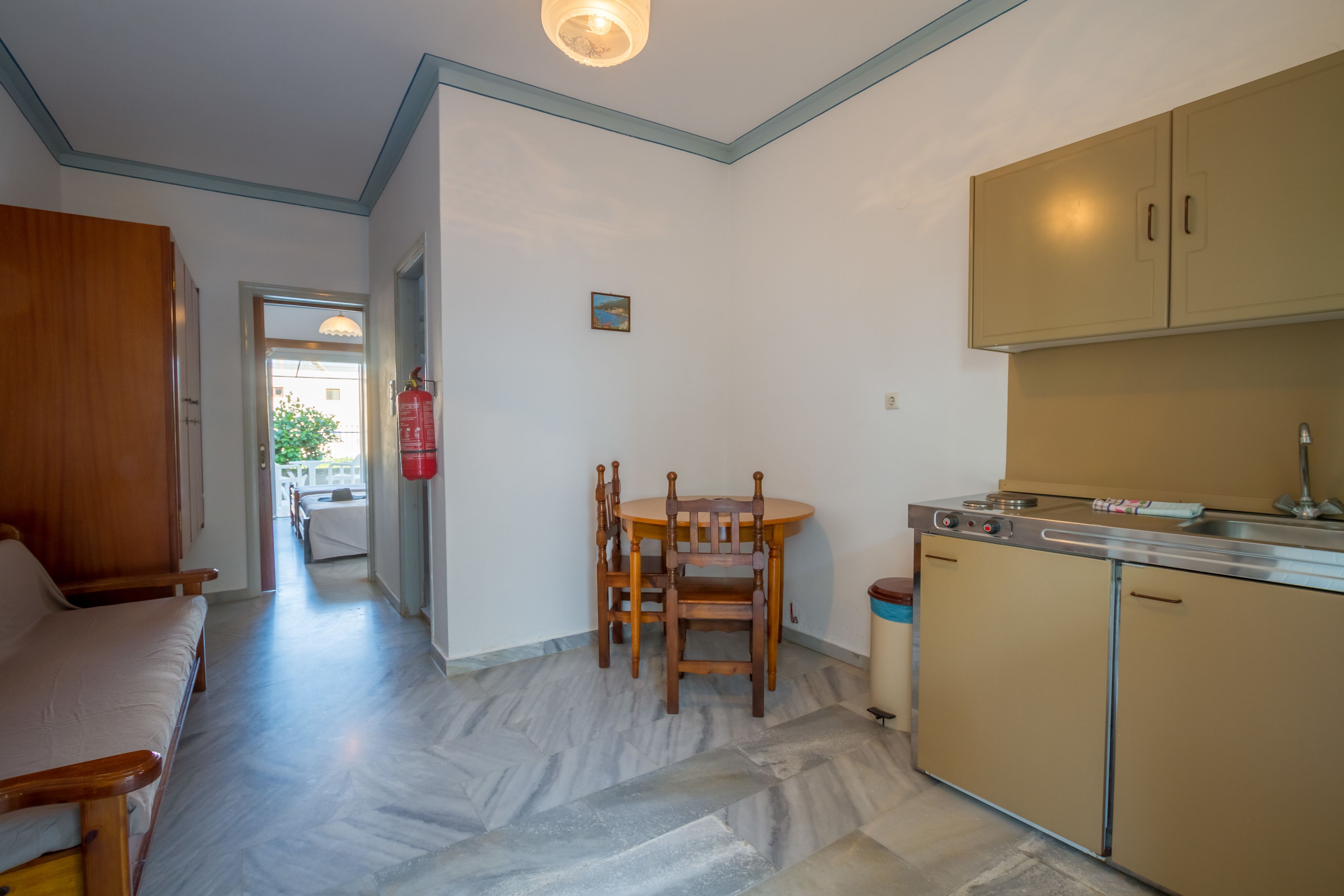 A compact kitchen with a dining area, wooden furniture, and a herringbone floor pattern.