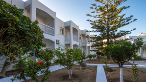 A hotel courtyard with white balconies, small trees, and a pathway. - Irene Hotel (Leros)