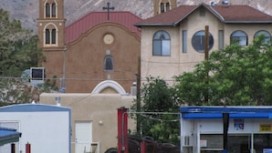 Uma igreja com duas torres sineiras e um edifício com telhado vermelho à frente.