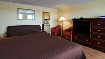 Une chambre d’hôtel avec un grand lit, une commode en bois, un bureau, une chaise, une lampe et un miroir.