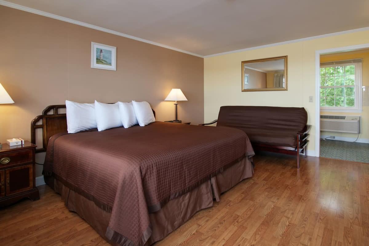 A hotel room with a large bed, two bedside tables, a chair, a mirror, and a window.