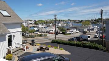 A marina with boats docked, a parking area with cars, and a building with a porch.