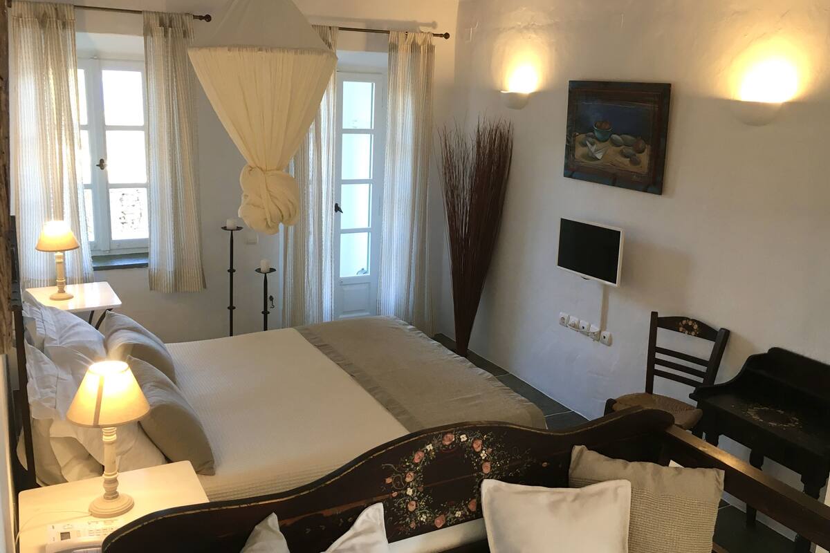 Ein Schlafzimmer mit einem Bett, Nachttischlampen, einem Fernseher und einem Klavier.