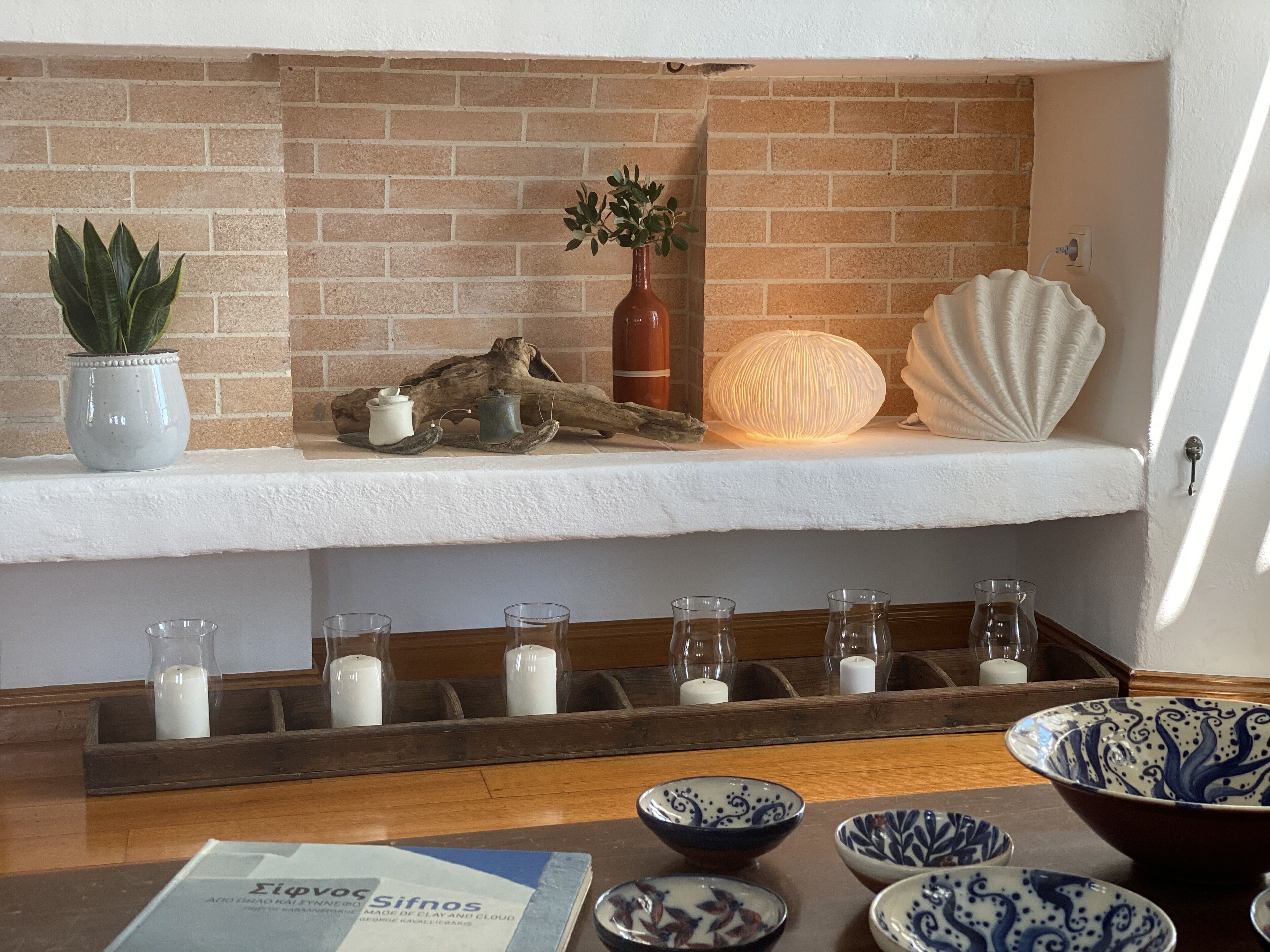 Una estantería con adornos, una bandeja de madera con velas y una mesa con cuencos y un menú.